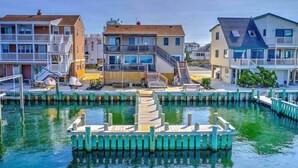 Ein Wohnhaus direkt am Wasser mit einem zentralen Steg, mehreren Balkonen und einer Treppe, die zu den oberen Etagen führt.