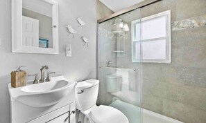 Une salle de bain moderne avec une douche à parois de verre, un lavabo blanc et des toilettes.