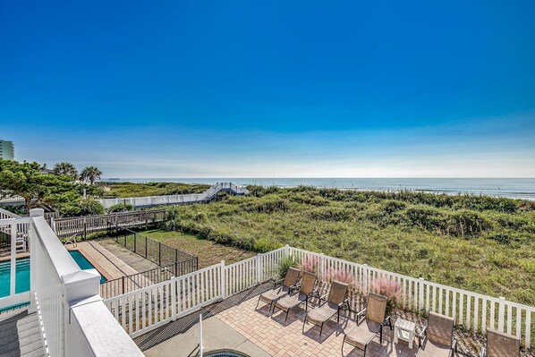 A pool area with a view of the beach and ocean.