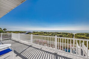 A wooden deck with white railings overlooking a beach.