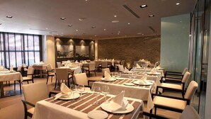 A dining area with tables set for service, a brick wall, and large windows. - Domus Selecta Hotel La Trufa Negra (Mora de Rubielos)