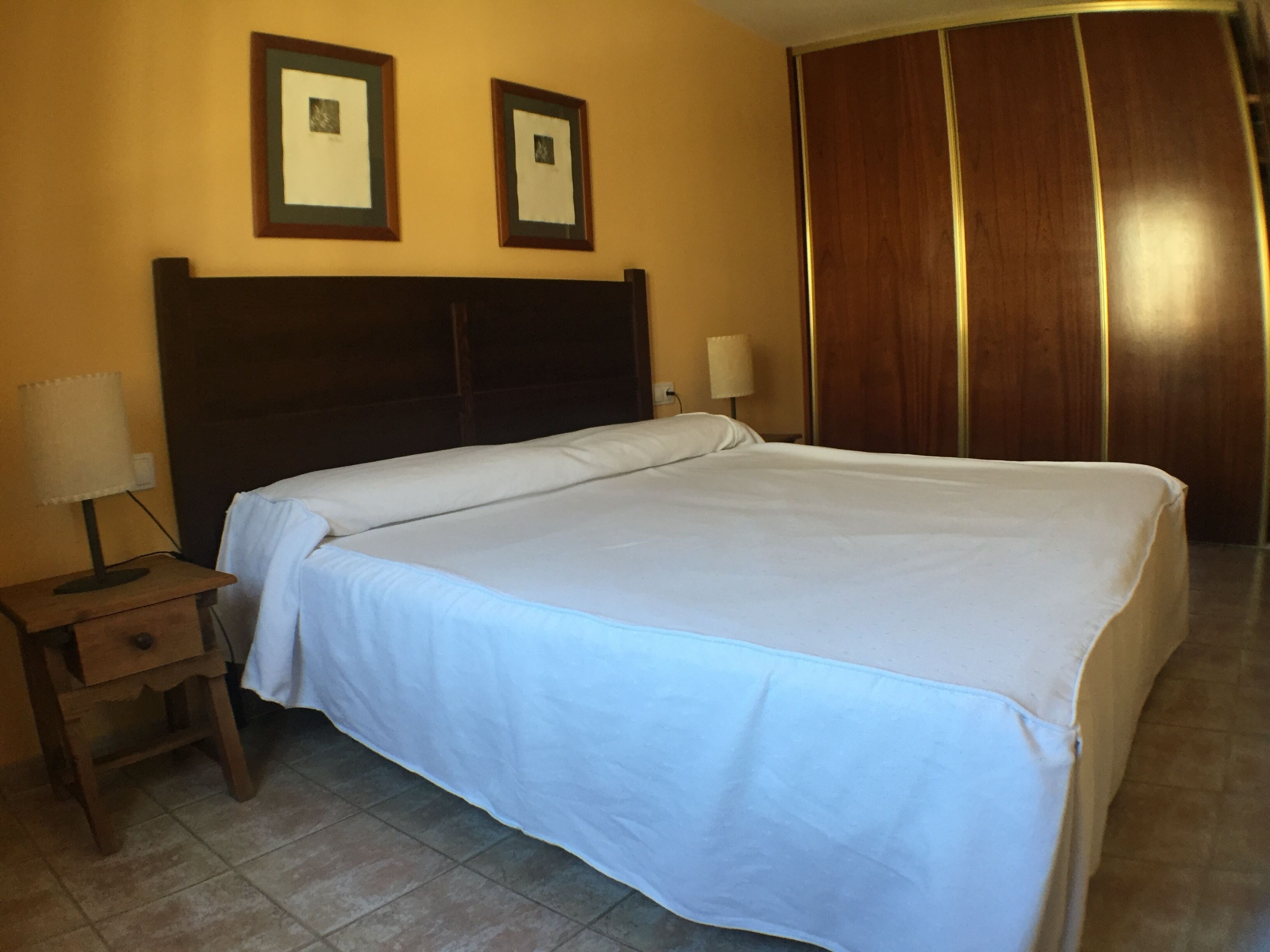 A hotel room with a bed, a nightstand, a lamp, and a wardrobe.