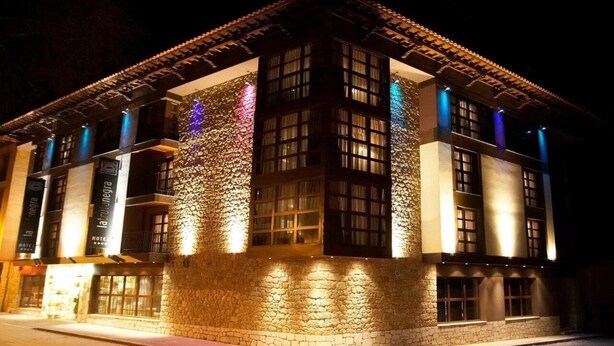 A hotel with a stone facade, multiple windows, and illuminated signage. - Domus Selecta Hotel La Trufa Negra (Mora de Rubielos)