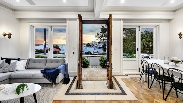A modern living room with a gray sofa, a coffee table, and a dining area with a white table and black chairs.
