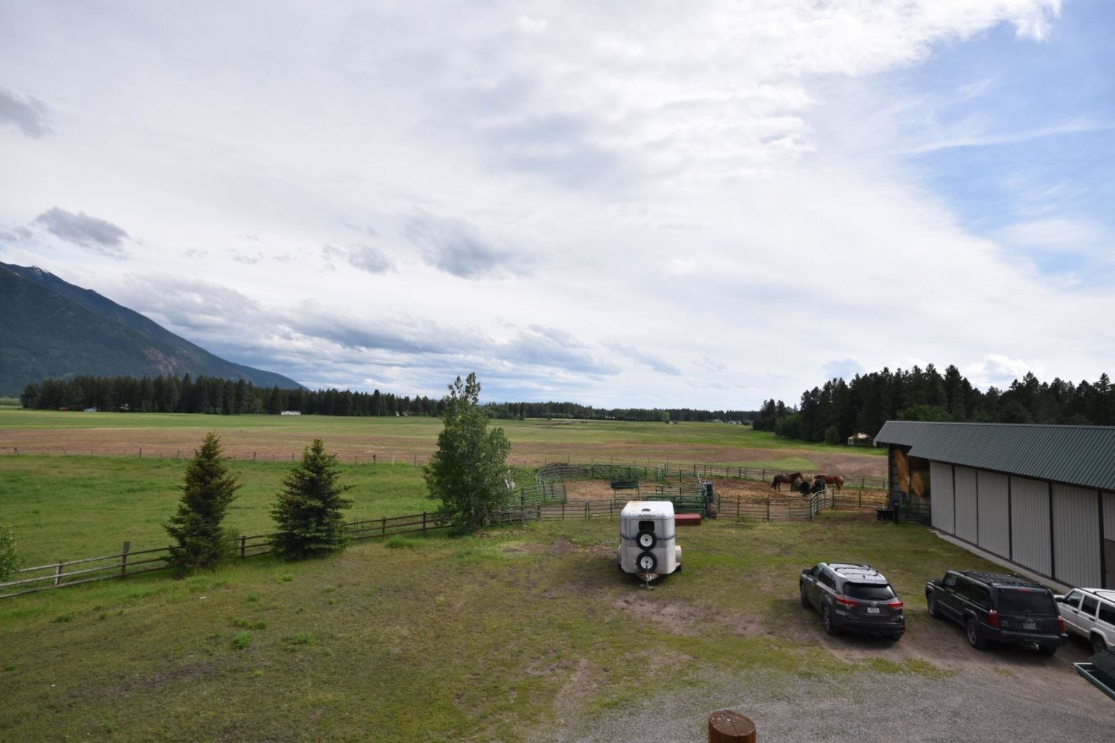 A rural property with a fenced pasture, a stable, and a building with a metal roof.