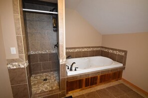 Un bagno con doccia a filo pavimento, una vasca freestanding e pavimento piastrellato.