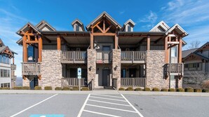 A multi-story hotel with a stone facade, balconies, and a parking lot in front. - Chalakee Lodge CI-1- Mountain View, Gated Resort, Indoor/Outdoor Pools & Hot Tub (Boone)