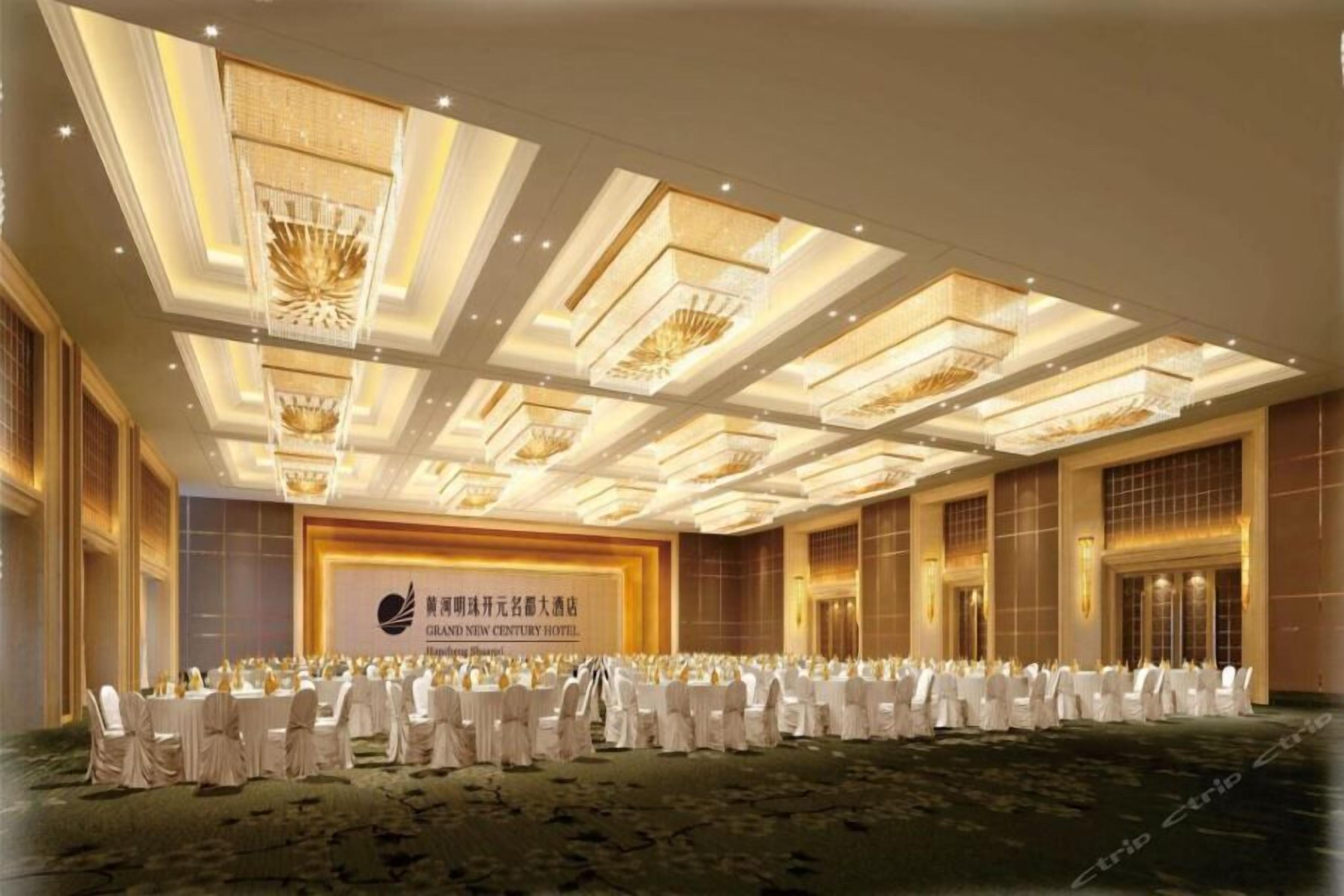 A large conference room with a stage, rows of white chairs, and a chandelier.