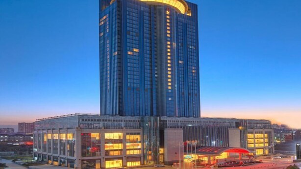 A high-rise building with a curved top, multiple floors, and a glass facade. - Grand New Century Hotel Hancheng Shaanxi (Weinan)