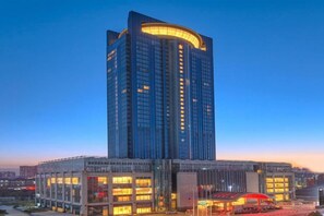 A high-rise building with a curved top, multiple floors, and a glass facade. - Grand New Century Hotel Hancheng Shaanxi (Weinan)