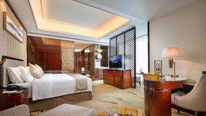 A hotel room with a bed, a desk, a chair, a TV, and a decorative screen. - Grand New Century Hotel Hancheng Shaanxi (Weinan)