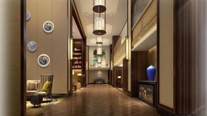 A spacious hallway with wooden flooring, a central light fixture, and a blue vase on the right. - Grand New Century Hotel Hancheng Shaanxi (Weinan)