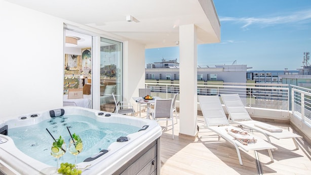 A balcony with a hot tub, lounge chairs, and a table with fruit.