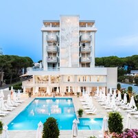 Un hôtel moderne doté d’une grande piscine, de nombreux balcons et d’espaces extérieurs aménagés pour se détendre.