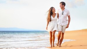 A couple walking on a sandy beach with the ocean in the background. - Life Hotel (San Michele al Tagliamento)