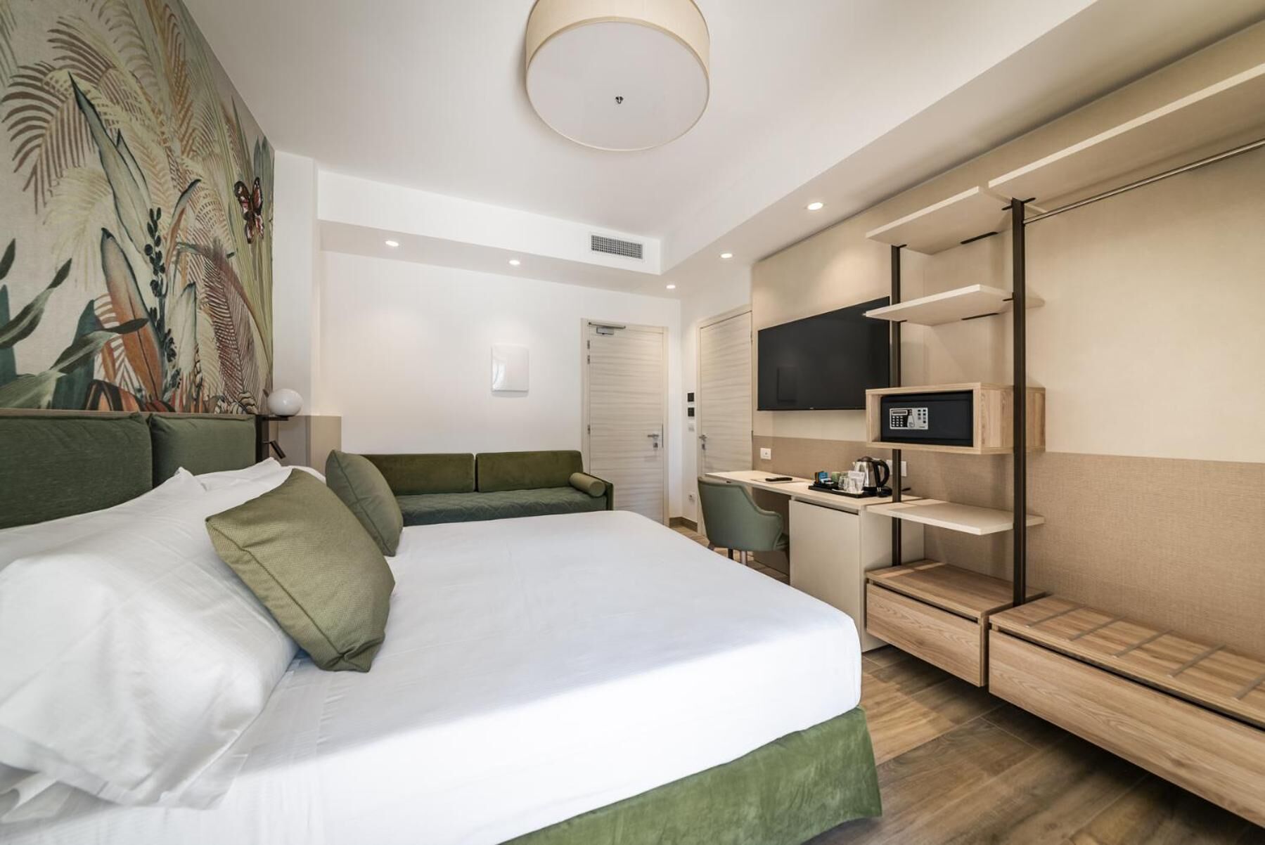 A hotel room with a bed, a desk, a TV, and a wardrobe.