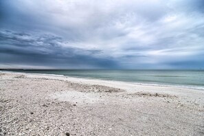 Una playa de guijarros y un mar tranquilo bajo un cielo nublado.
