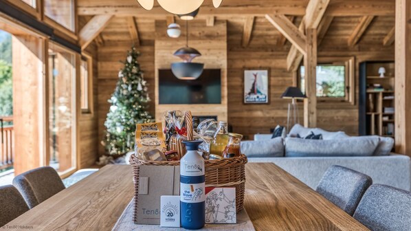 A wooden interior with a dining table set for a meal, a Christmas tree, and a cozy seating area.