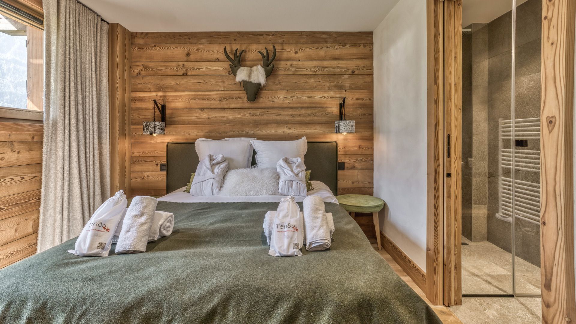 Une pièce en bois avec un lit, une tête de cerf accrochée au mur et un porte-serviettes avec des serviettes.