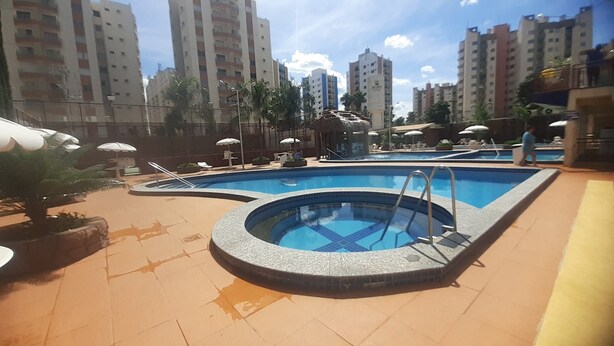 Una piscina en la azotea con varias pistas, rodeada de palmeras y sillas de descanso.