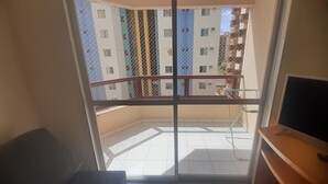 Un balcón con barandilla de metal, suelo de baldosas y vistas a edificios de varios pisos.