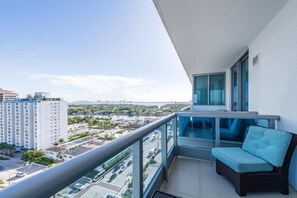 Enjoy the city view from this balcony with a wicker sofa and glass balustrade.