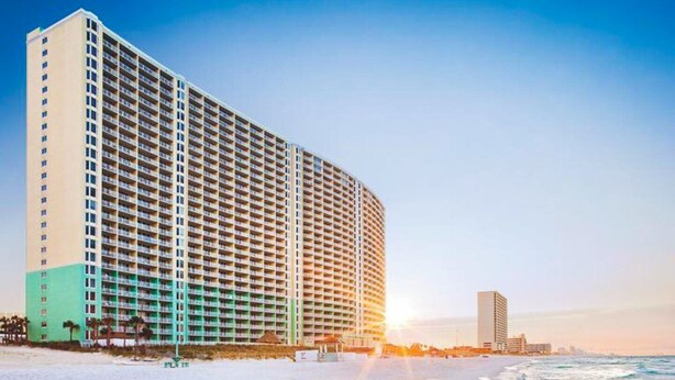 Ein Hochhaus-Hotel mit mehreren Etagen, direkt neben einem Strand und Blick auf den Ozean.