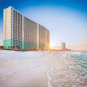 Ein Hochhaus-Hotel mit mehreren Etagen, direkt neben einem Strand und Blick auf den Ozean.