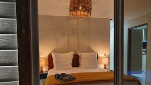 Una camera da letto con un letto, cuscini, una coperta e un comodino con una lampada.