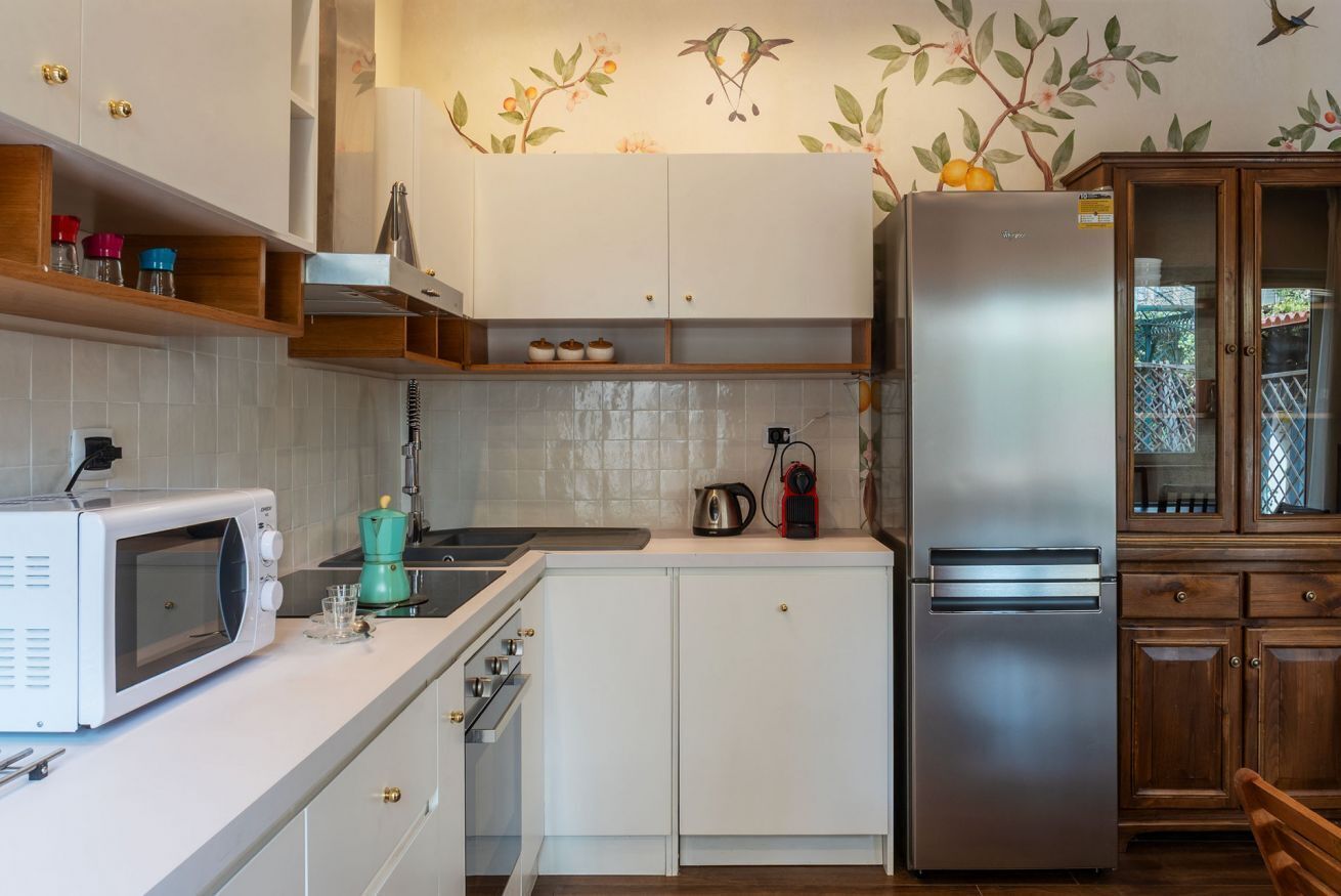 A compact kitchen with white cabinets, a stainless steel refrigerator, a microwave, and a coffee maker.
