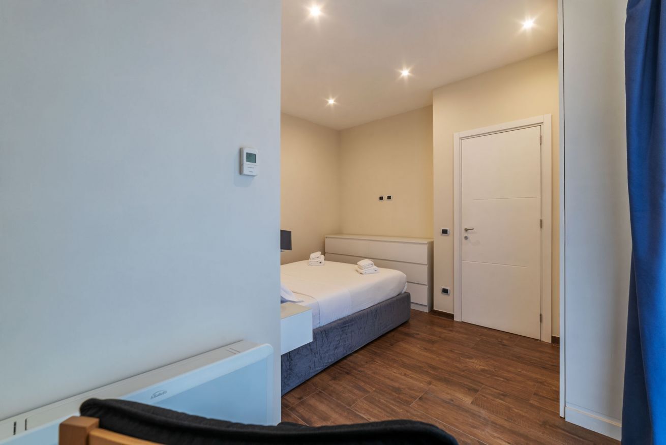 A bedroom with a bed, bedside table, and a door.