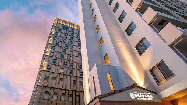 Et moderne hotel med en høj, rektangulær bygning, karakteriseret ved et gitter af vinduer og et fladt tag.