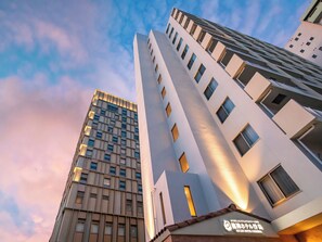 A modern hotel with a tall, rectangular building featuring a grid of windows and a flat roof.