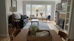 Una sala de estar con sofá, sillones, una mesa de centro, chimenea y un ventanal grande.
