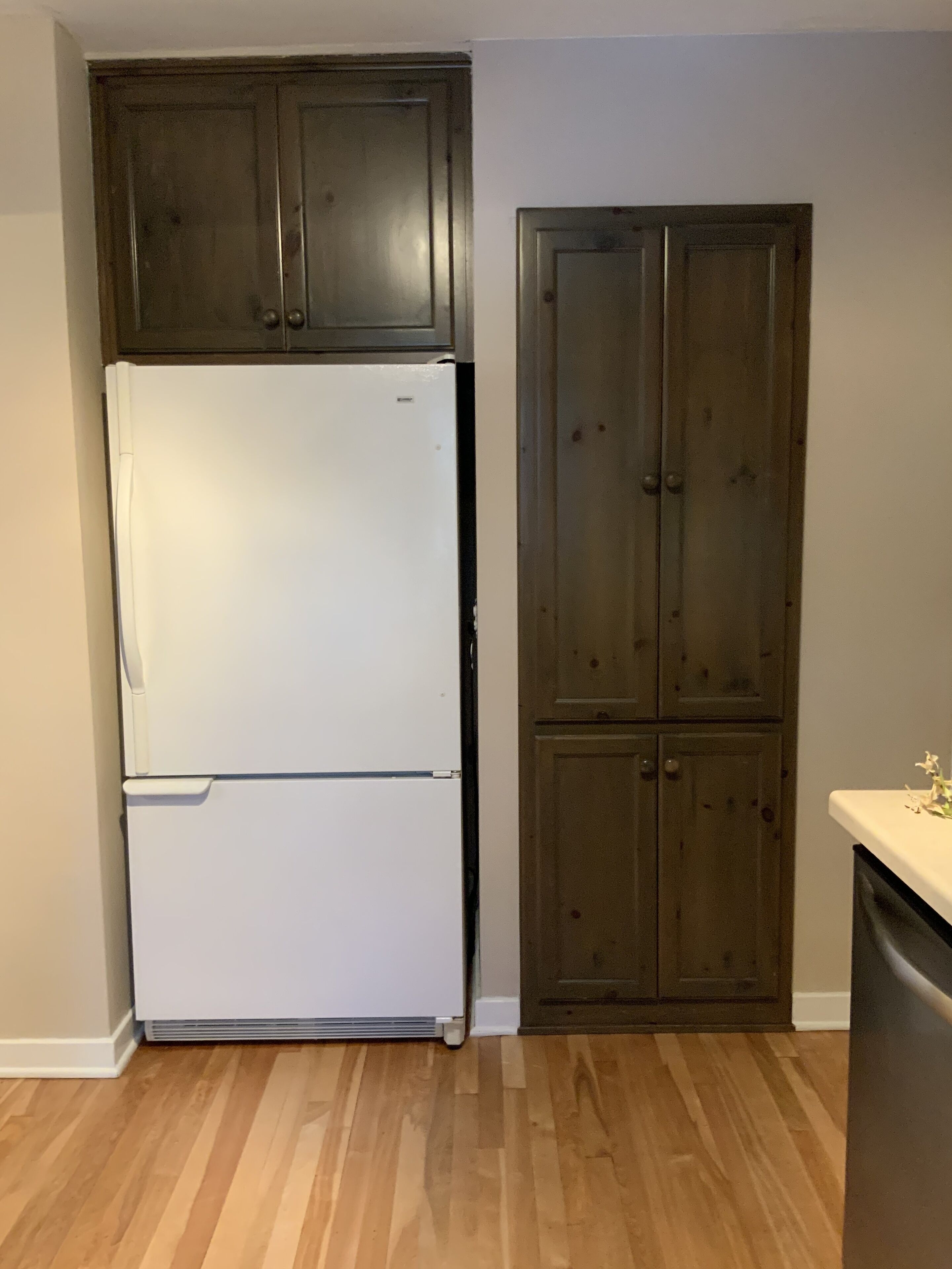 A kitchen with a white refrigerator, wooden cabinets, and a wooden floor.