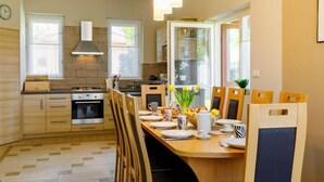 Une cuisine moderne avec des meubles en bois, un four encastré et un coin repas comprenant une table et des chaises en bois.