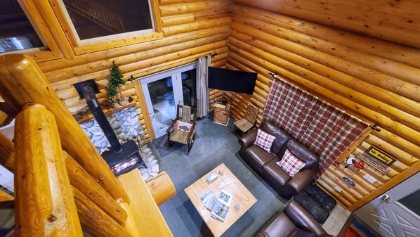 Interior acogedor de una cabaña de madera con chimenea, un sofá de cuero y una pequeña mesa con revistas.