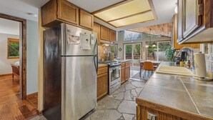 Una cocina moderna con armarios de madera, un refrigerador de acero inoxidable, horno empotrado y salpicadero de baldosas de piedra.