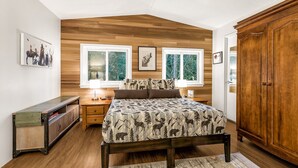 Une chambre à coucher avec une tête de lit en bois, un lit avec une literie à motifs, une table de chevet, une commode et une armoire.