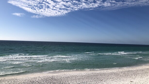 Une plage avec un ciel dégagé et des vagues.