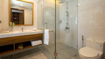 Een moderne badkamer met een douchecabine van glas, een houten wastafelmeubel, een toilet en een grote spiegel.