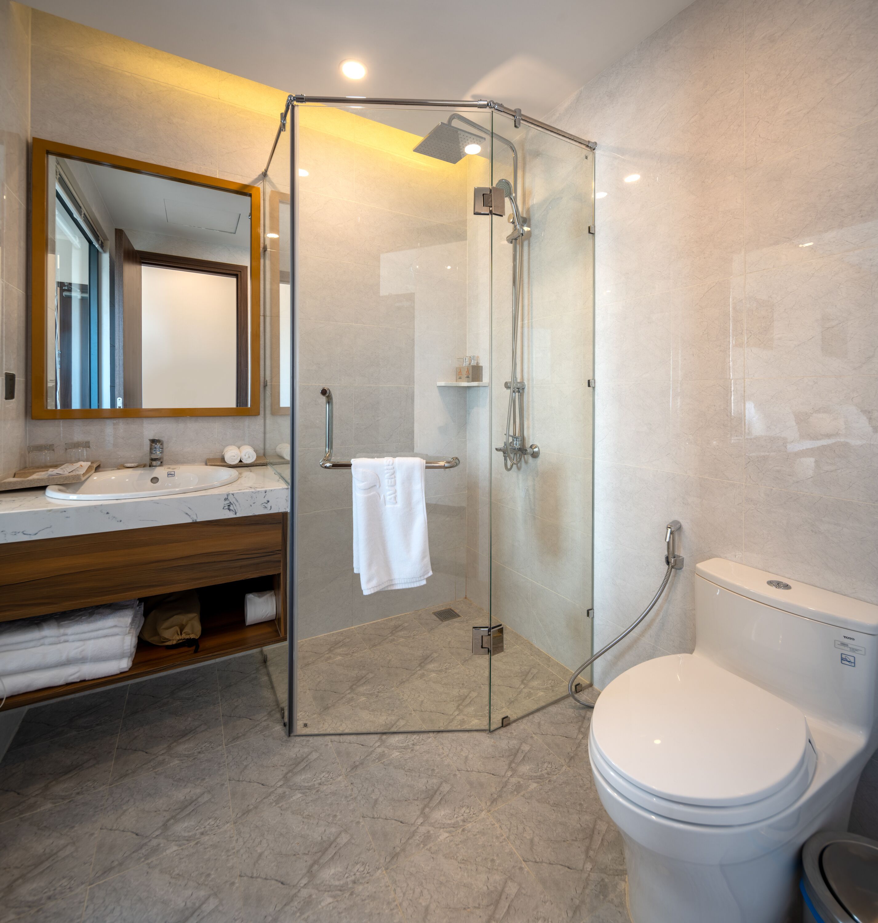 Une salle de bain moderne avec une douche à parois de verre, des toilettes blanches et un sol carrelé en marbre.