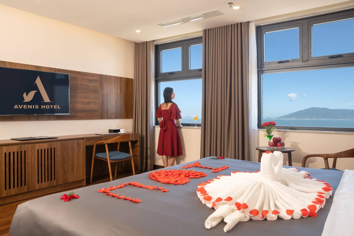 Habitación de hotel con cama, escritorio, televisor y ventana con vistas.