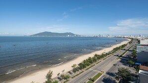 Un paisaje costero con playa, una montaña a lo lejos y cielo despejado.