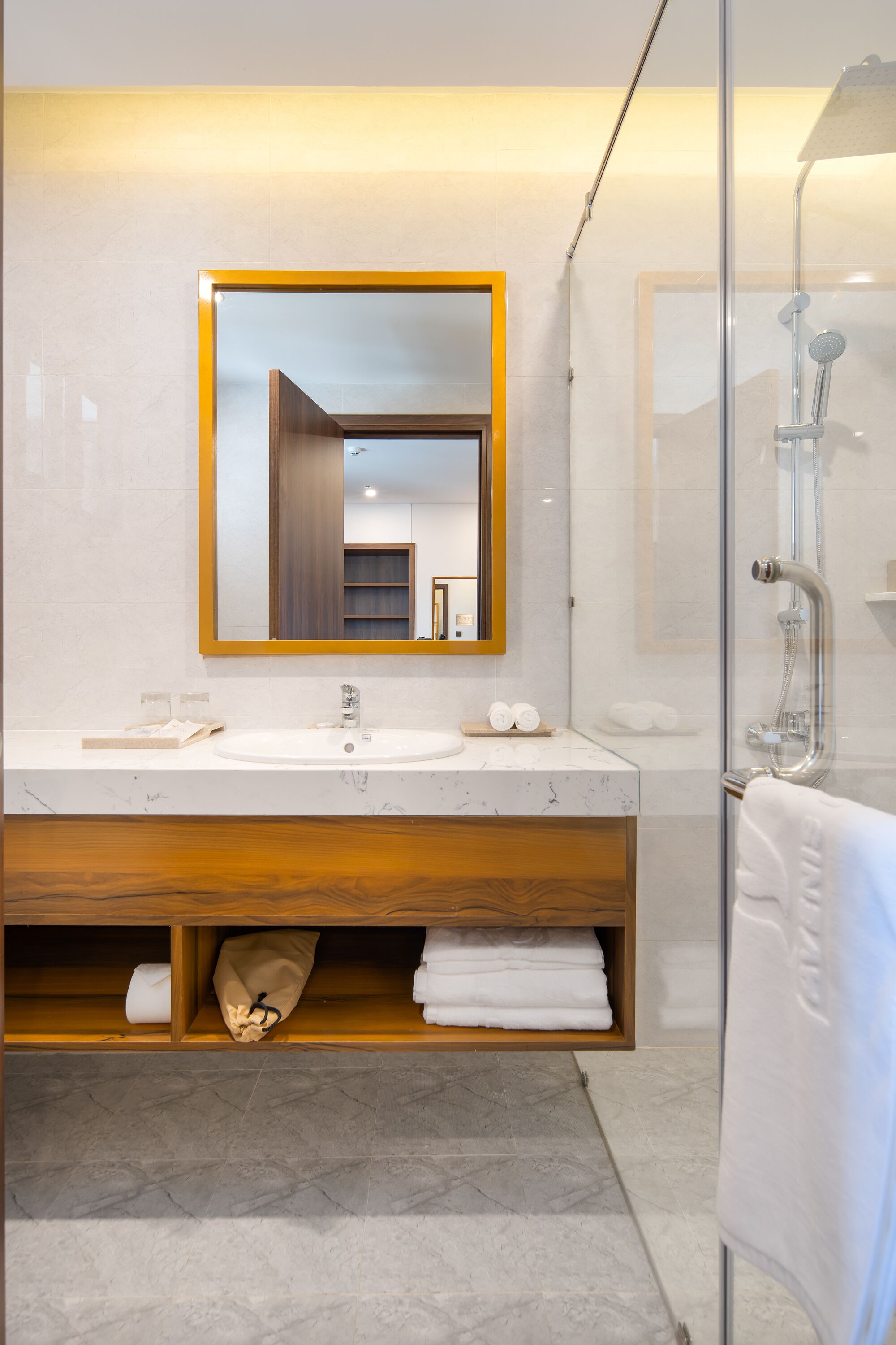 Een moderne badkamer met een marmeren wastafelmeubel, een grote spiegel en een douchecabine van glas.