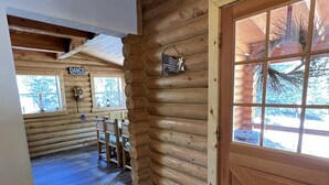 A log cabin interior with a wooden door, a rug, and a sign that says "DANCE JUST DANCE". - Hot Tub at Our Family cabin. It’s great for all family sizes and year round fun! (Duck Creek Village)