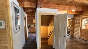 A wooden interior with a hallway leading to a staircase and a door. - Hot Tub at Our Family cabin. It’s great for all family sizes and year round fun! (Duck Creek Village)