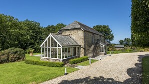 Un bâtiment en pierre doté d’une véranda en verre et d’une allée gravillonnée.