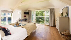 Une chambre à coucher avec un grand lit, une commode, un téléviseur et une fenêtre avec des rideaux.
