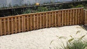 A beachfront property with a white fence, sandy beach, and a wooden boardwalk. - Affordable 2 bed, 1.5 bath Beach views. Hot tub, Pet friendly, fenced back yard. (Saint George Island)